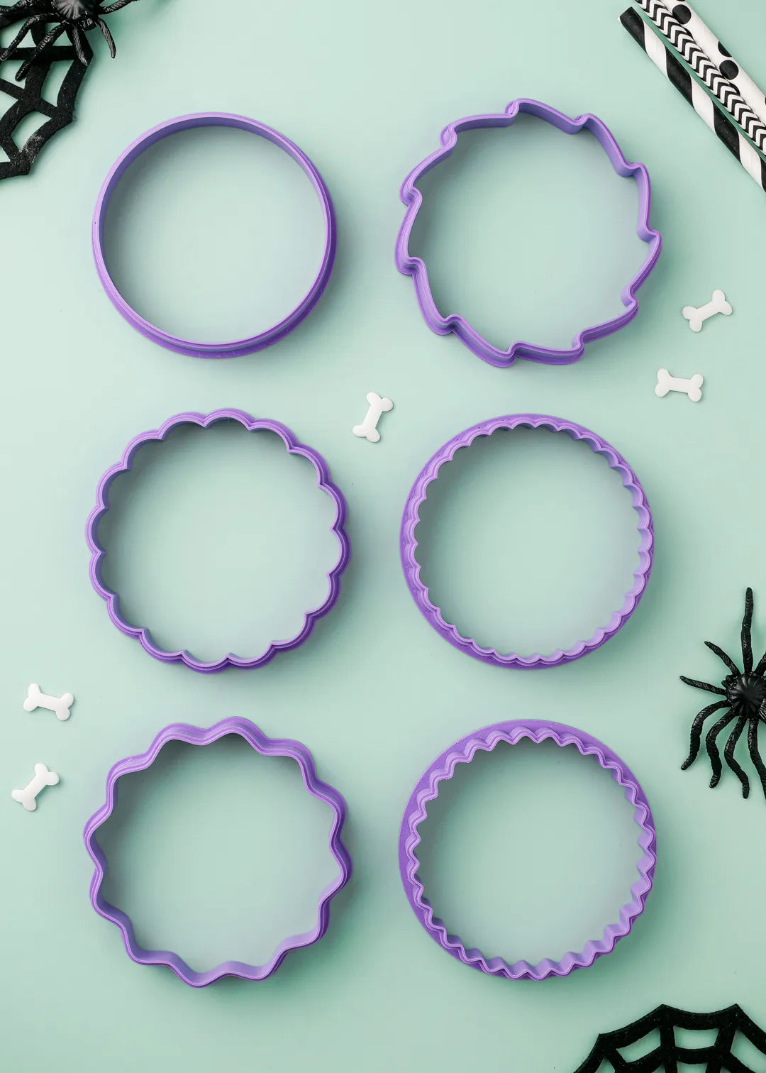 6 options of purple cookie cutters on a light green background with Halloween decorations.