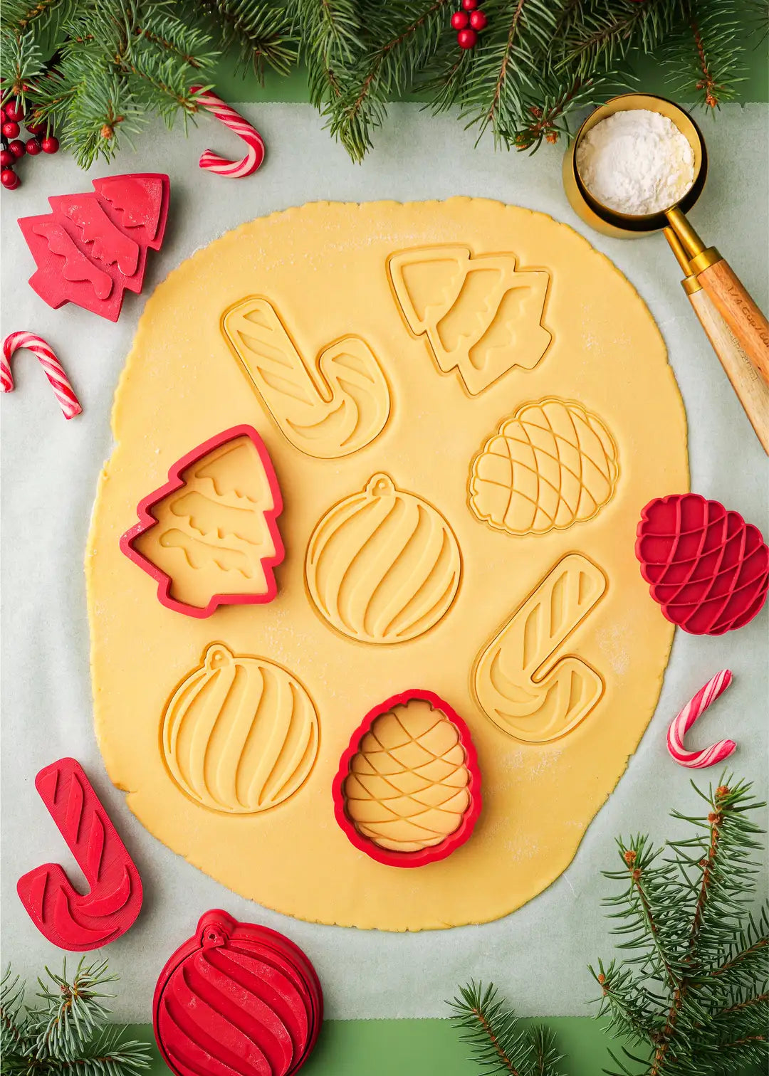 Demonstration of cookie stamps and cutters pressed on rolled out sugar cookie dough. The stamps create swirly shaped imprints which after baking can be filled with icing or jam.