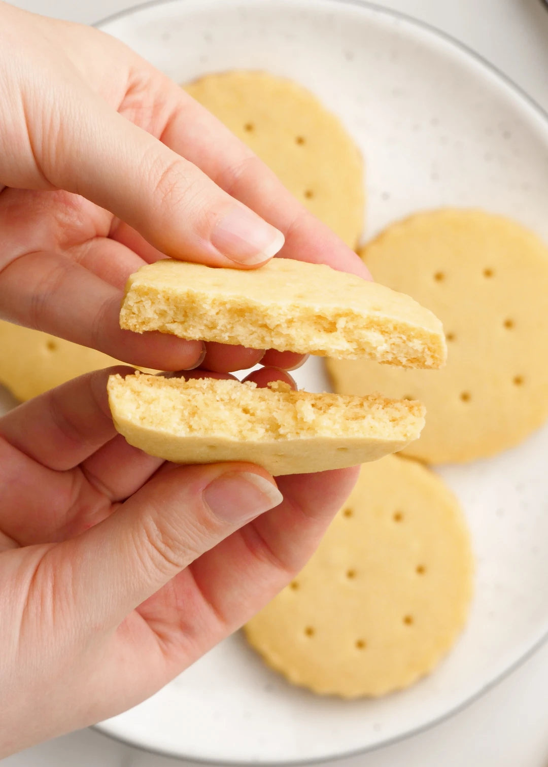 close-up shot of breaking a cookie apart so that the buttery crumbly texture is revealed