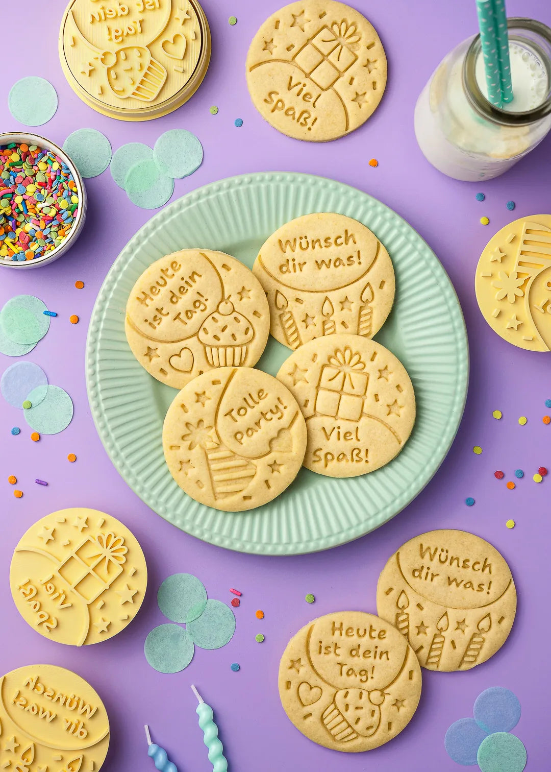A plate filled with embossed cookies featuring birthday greetings, decorated with festive confetti and a bottle of milk. Perfect gift.