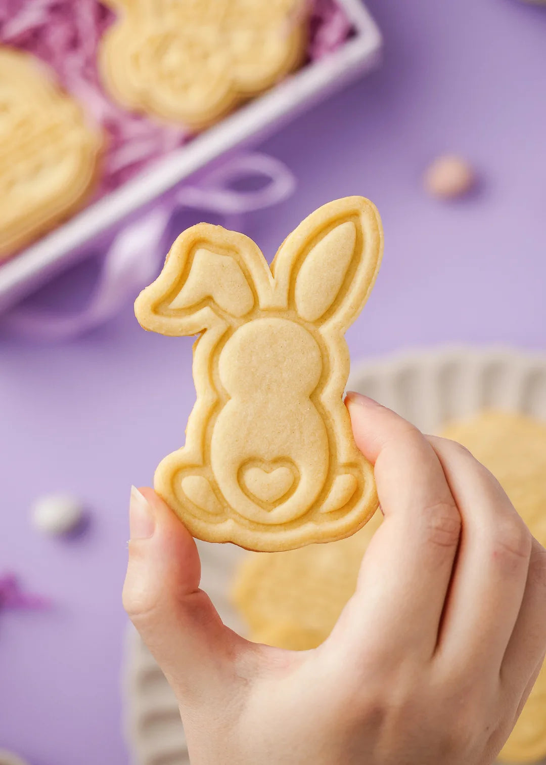 Easter bunny-shaped cookie with an embossed heart detail, held in hand. Perfect homemade cookie made with an Easter cookie cutter.