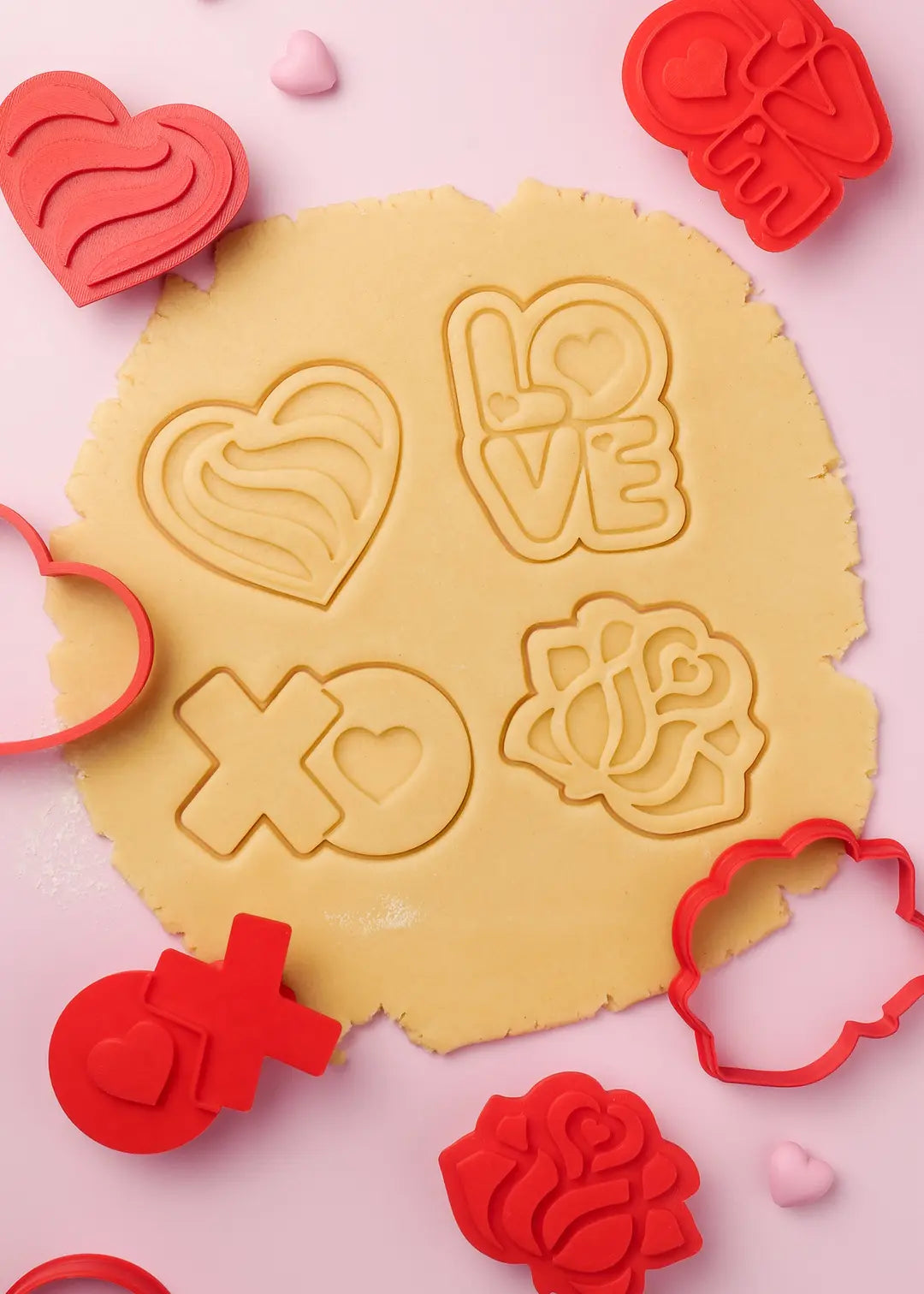 Embossed Valentine's cookie cutters pressing love-inspired designs onto dough – hearts, roses, and "I love you" messages.