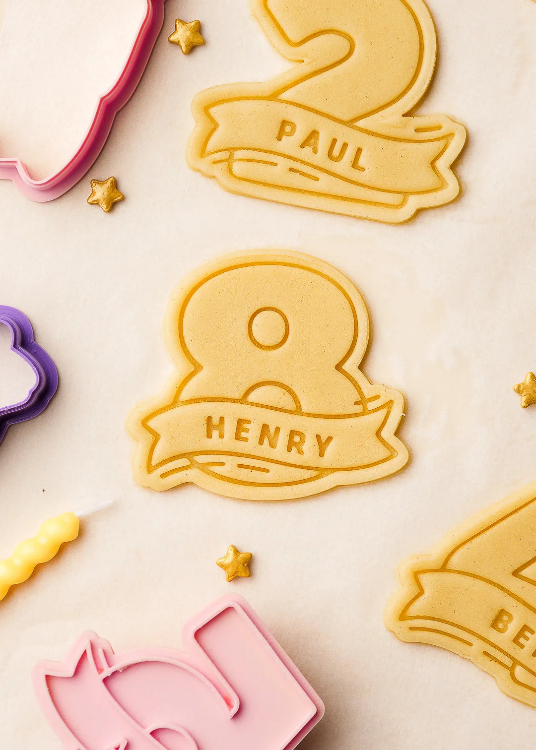 Number-shaped cookie dough with embossed names 'Henry' and 'Paul', precisely cut using custom 3D printed cookie cutters. Perfect for birthday party baking and personalized treats.