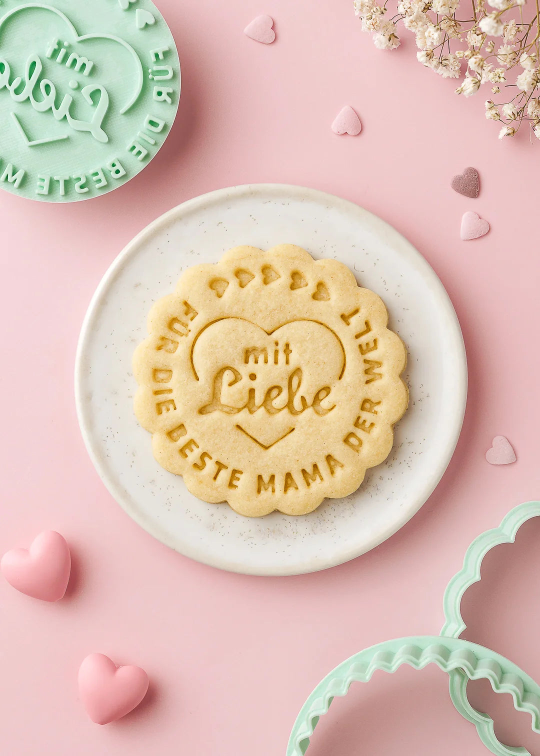 Stamped cookie with the message “Für die beste Mama der Welt” on a scalloped edge biscuit, made using our cookie stamp and cutter. A beautiful handmade gift or complimentary treat for Mother’s Day. The text is custom