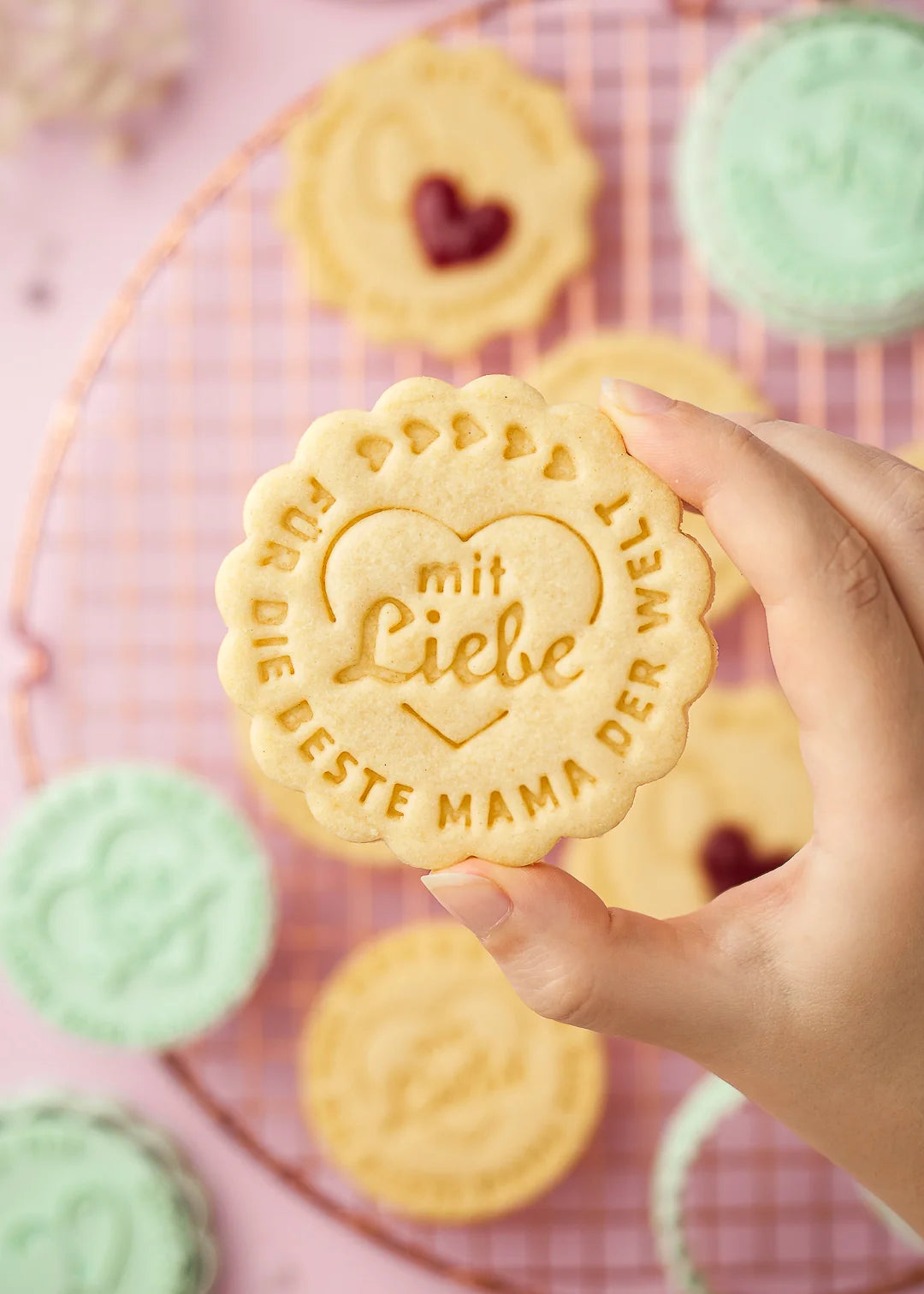 Hand holding a heart-stamped cookie with the German phrase “Für die beste Mama der Welt – mit Liebe”. Made with our customizable cookie stamp – a perfect treat for Mother’s Day or a heartfelt gift.