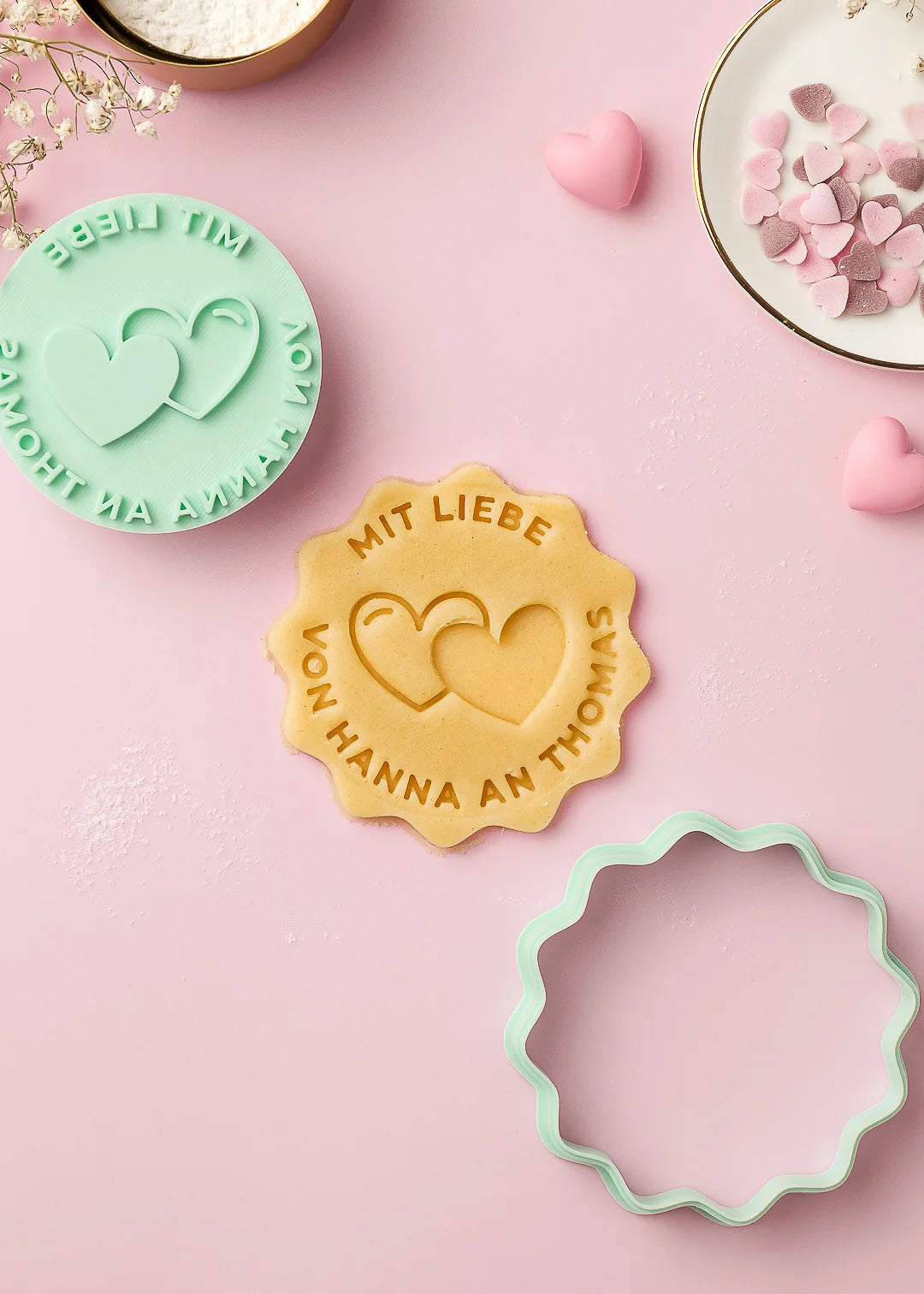 Custom cookie stamp “Mit Liebe – von Hanna an Thomas” with two hearts, shown with the matching cutter and a perfect imprint in cookie dough. A beautifully coordinated baking set for personalized cookies and heartfelt gifts.