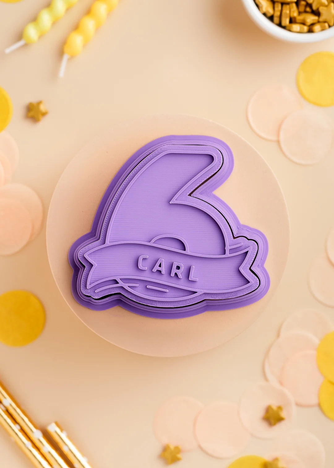 Purple number six cookie stamp with cutter with custom name 'Carl', perfect for a kids birthday party. Surrounded by pastel confetti and party-themed decorations.