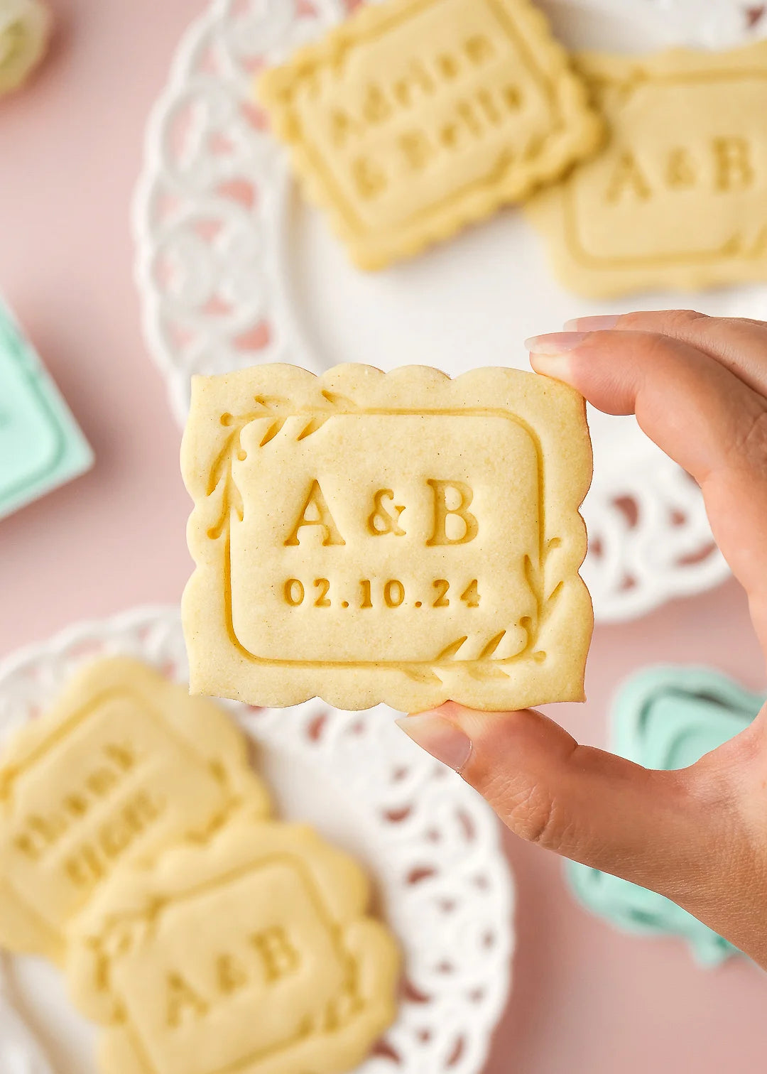 Baked cookie with initials A&B and date 02.10.24, made with custom wedding rectangular cookie stamp and a pillow frame cookie cutter.