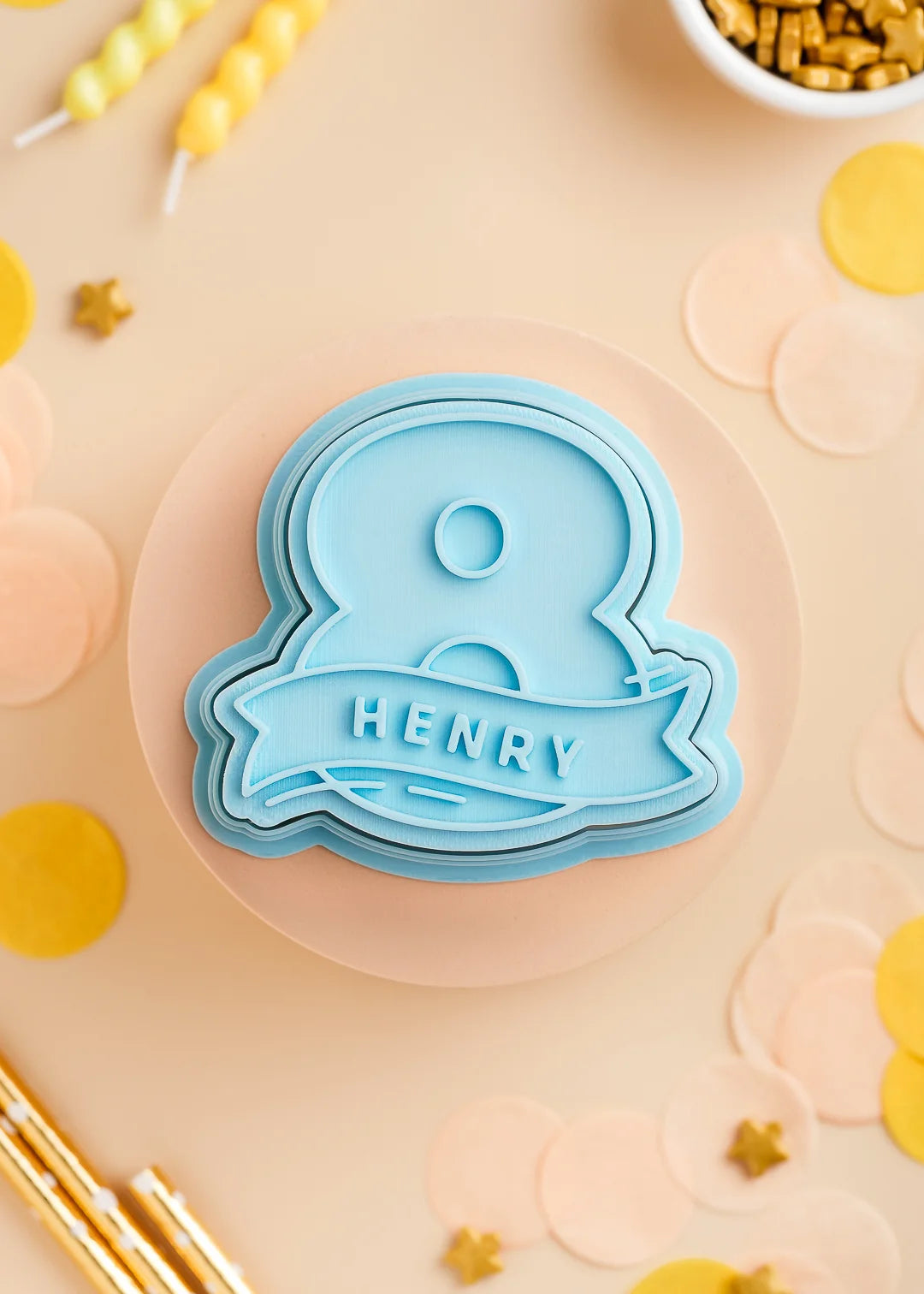 Pastel Blue number eight cookie stamp with cutter with custom name 'Paul', perfect for a kids birthday party. Surrounded by pastel confetti and party-themed decorations.