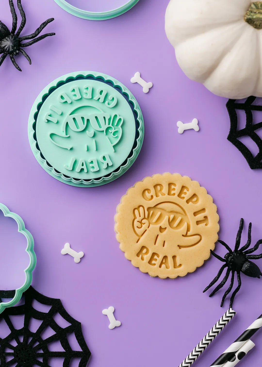 Halloween-themed cookies with 'Creep It Real' text on a purple background with spider decorations.