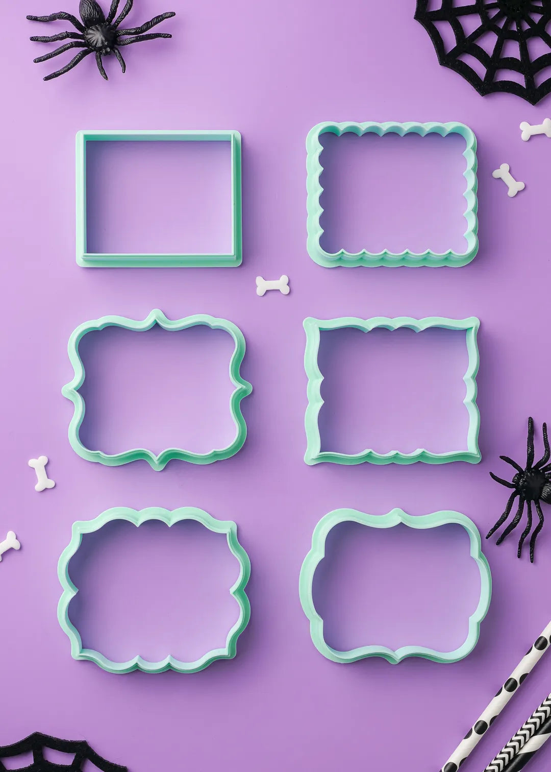 Six options of green cookie cutters on a purple background with Halloween decorations.