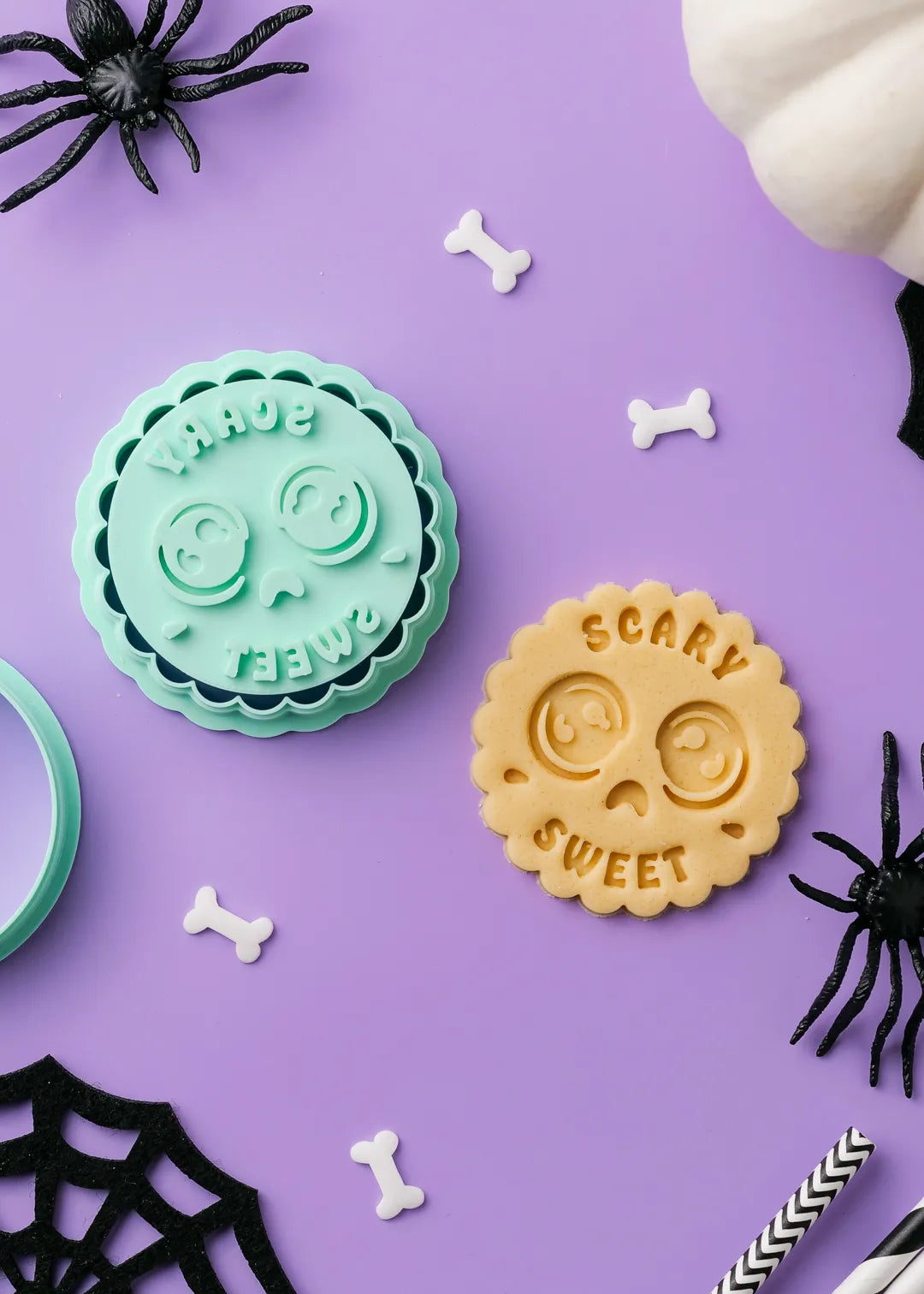 Halloween-themed cookie stamp with scared face emoji and "scary sweet" text next to a cookie made with the stamp on a purple background