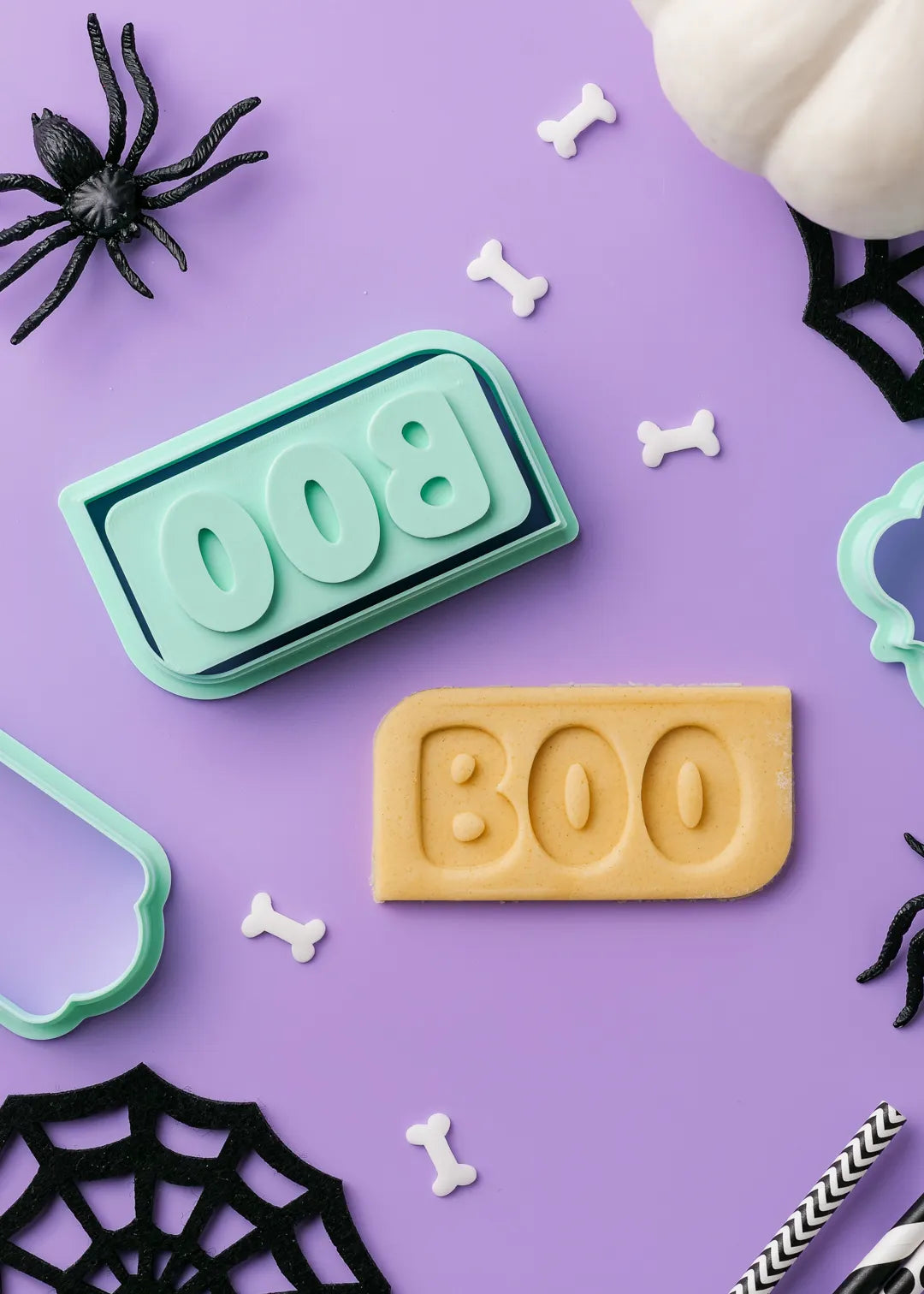 Halloween-themed cookie stamo stamp and cutter with 'BOO' phrase on a purple background