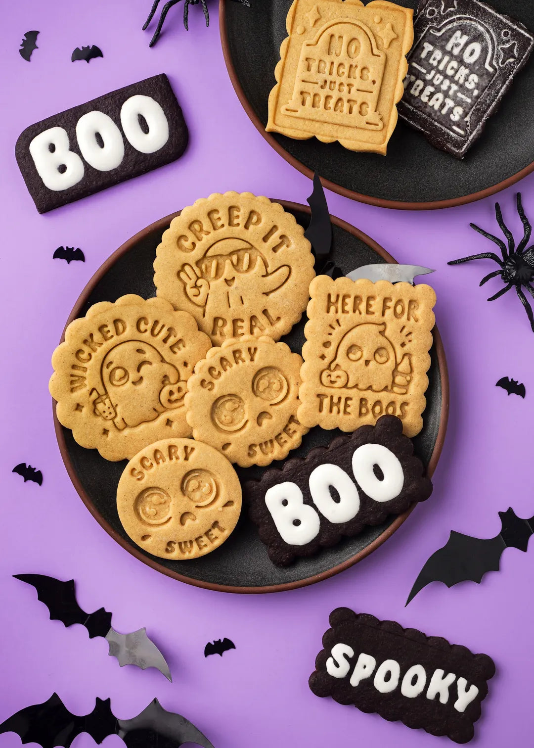 Halloween-themed decorated cookies on plate and on a purple background with decorative elements.