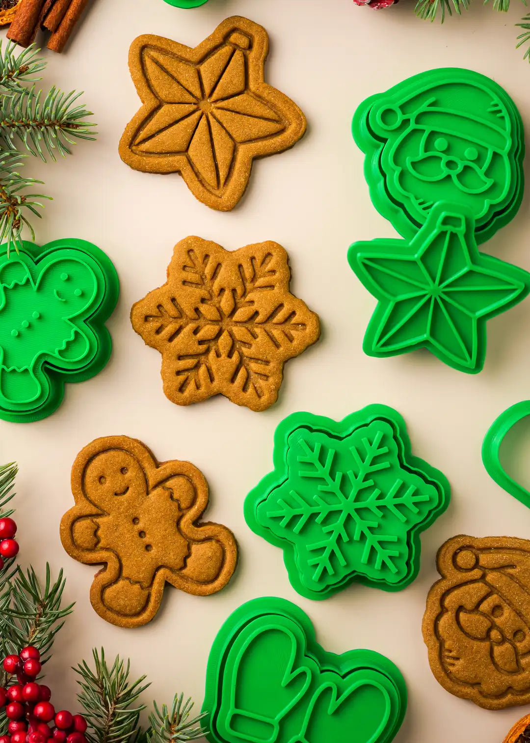 close up photo of baked cookies and the cookie cutters and stamps around them; snowflake, gingerbread man and christmas star cookies